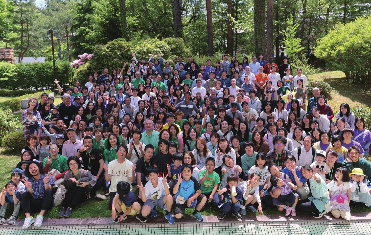 Conference attendees gathered for a group photo among trees