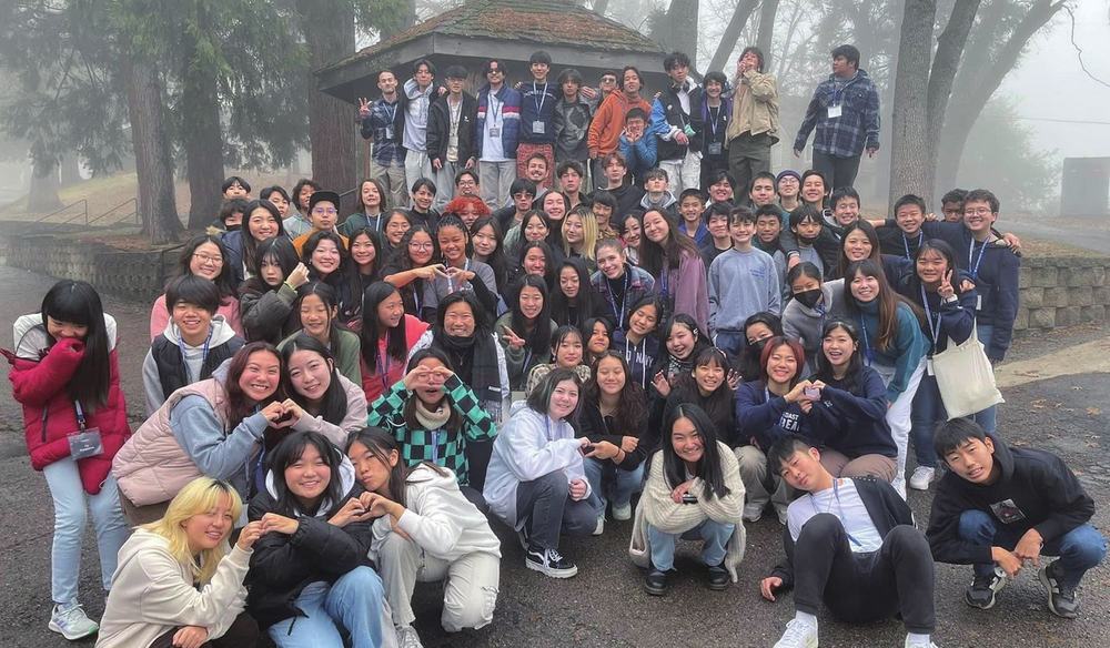 Group photo from a recent conference, gathered outdoors in mist