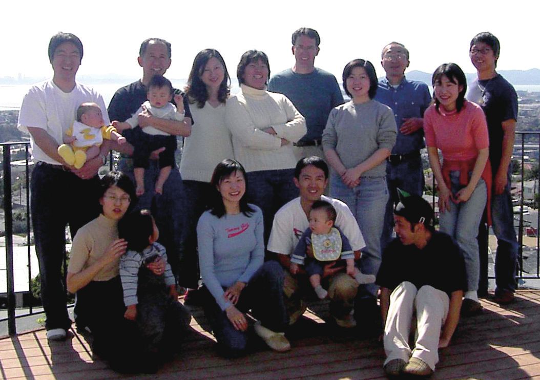 Three generations gathered together outdoors at a JCFN gathering, several holding babies